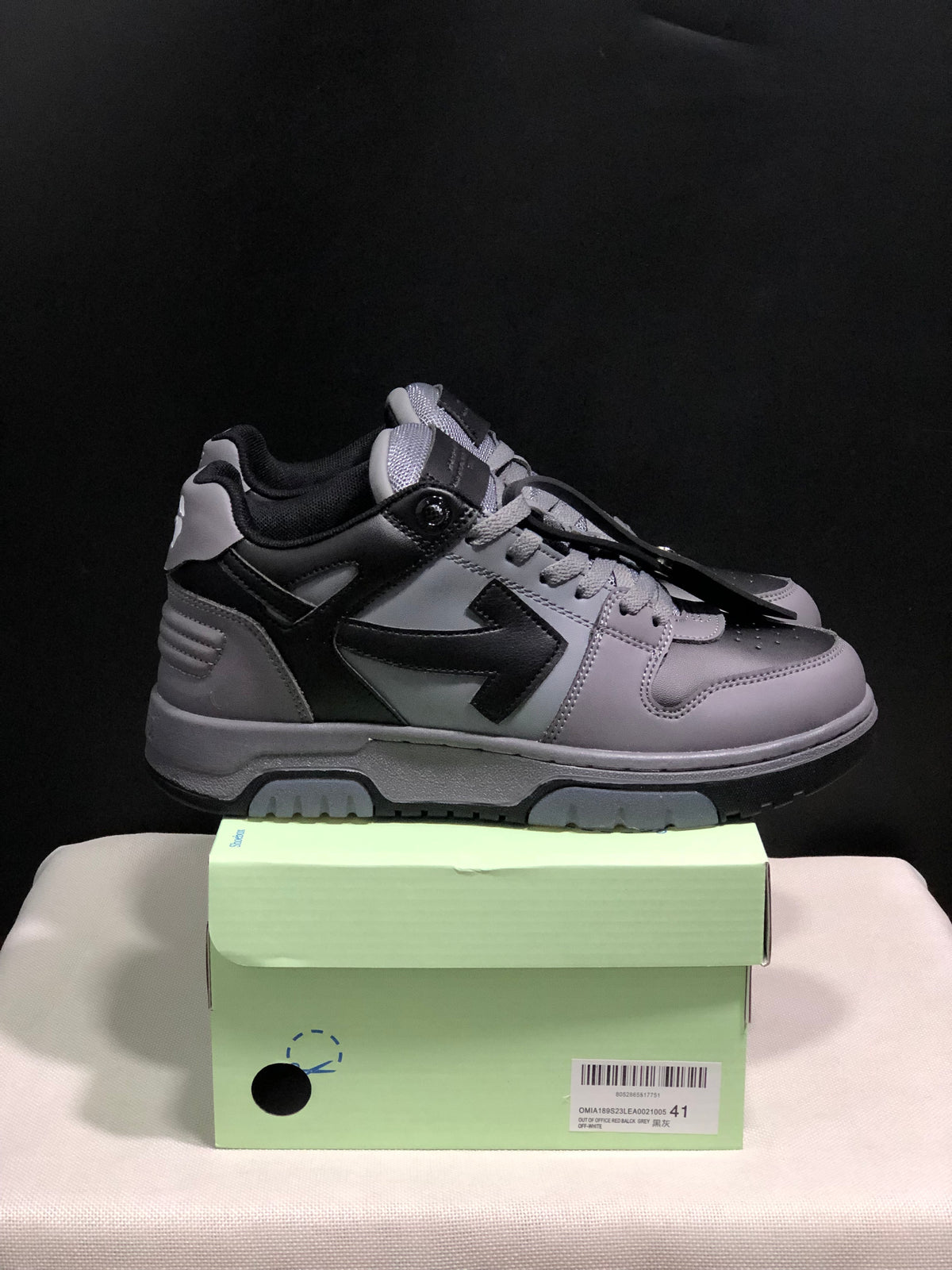 Side view of the grey and black low-top sneakers showing the layered side panels and padded collar.