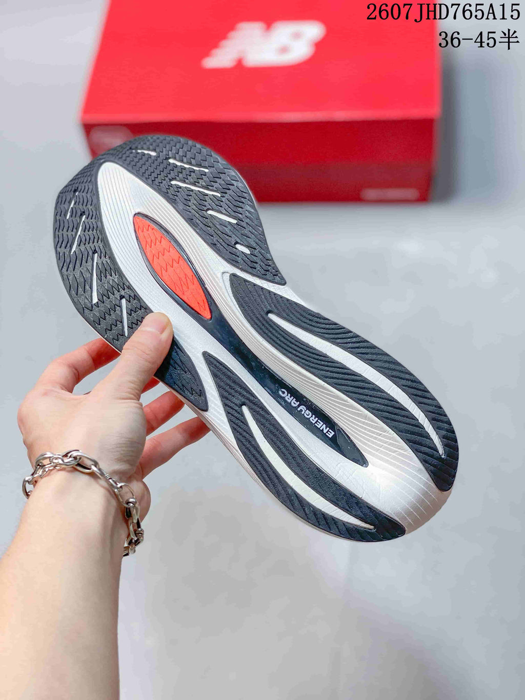 Close view of the black, white, and orange patterned outsole on a New Balance running shoe.