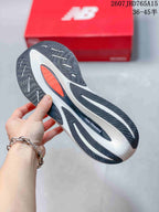 Close view of the black, white, and orange patterned outsole on a New Balance running shoe.