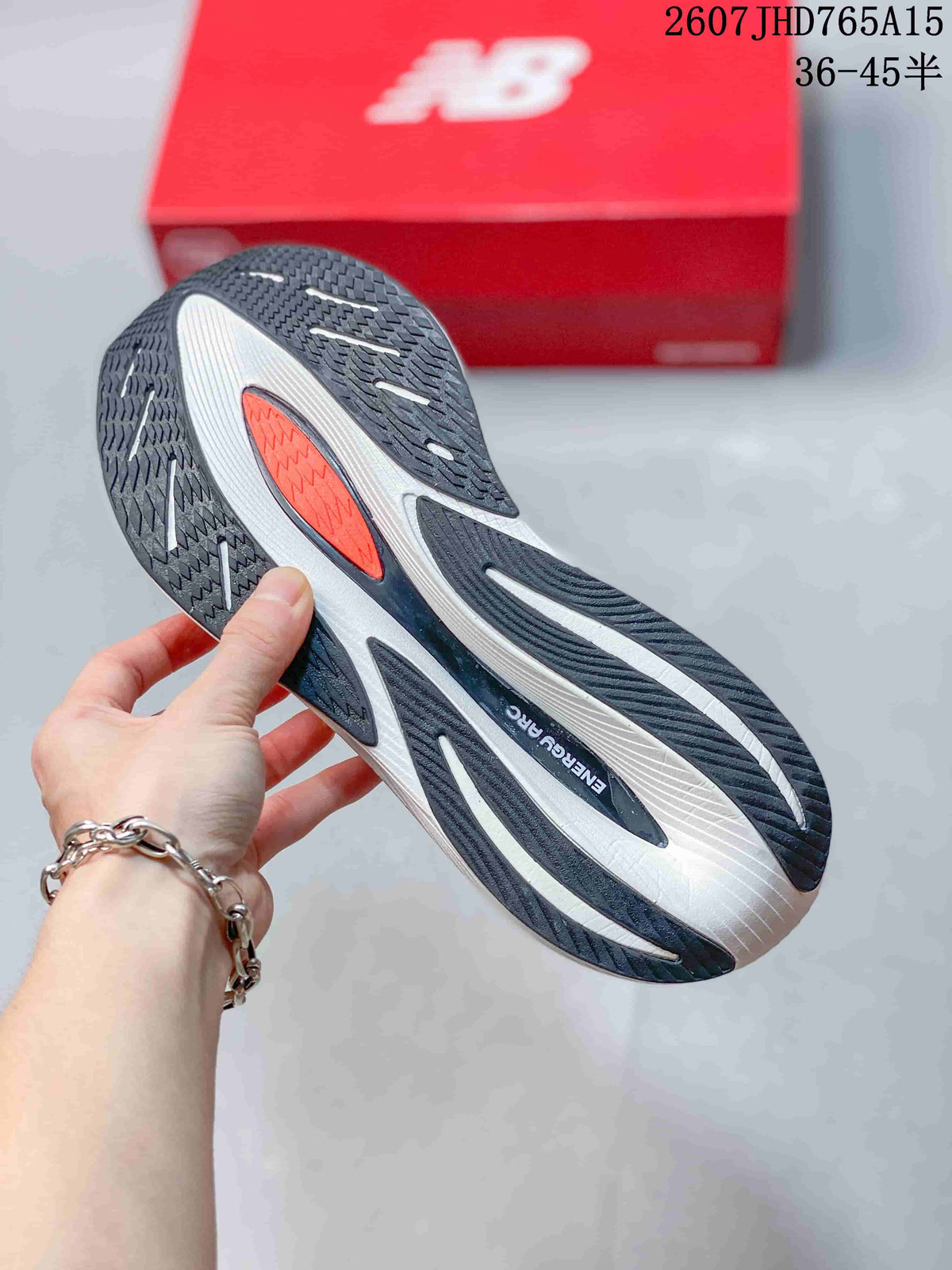 Close view of the black, white, and orange patterned outsole on a New Balance running shoe.