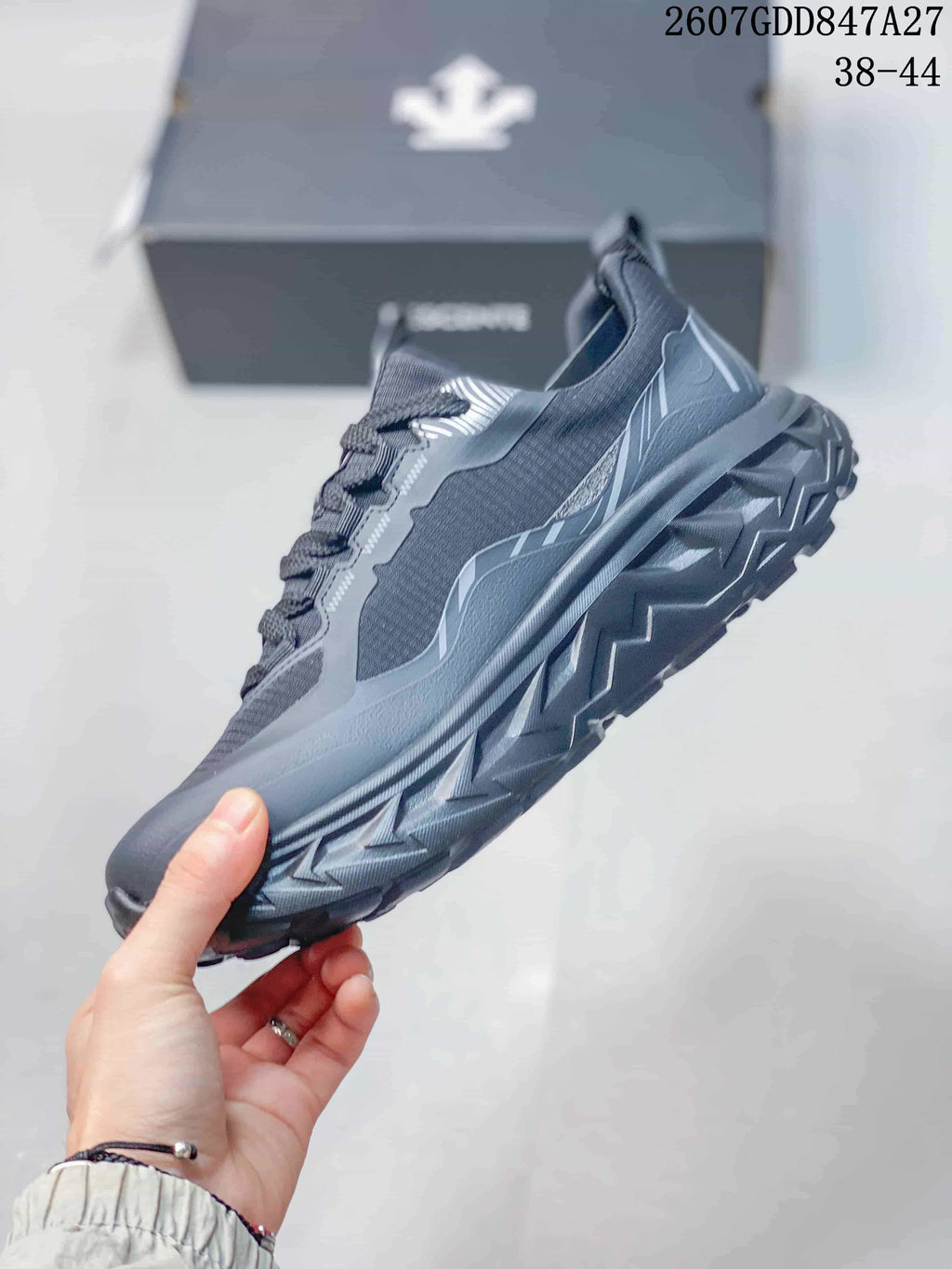 Side view highlighting the black low-top profile, layered panels, laces, and chunky outsole.