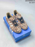 Pair of Adidas Samba OG sneakers with leopard-print uppers, black laces, white stripes, and a blue Adidas shoe box.