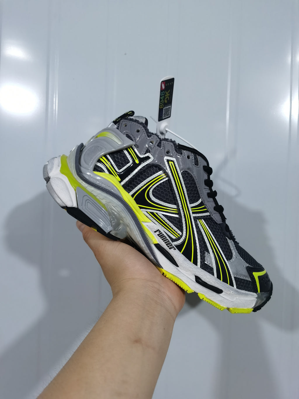 Opposite angled view showing the sneaker's mesh-look panels, side branding, grey overlays and neon yellow accents.