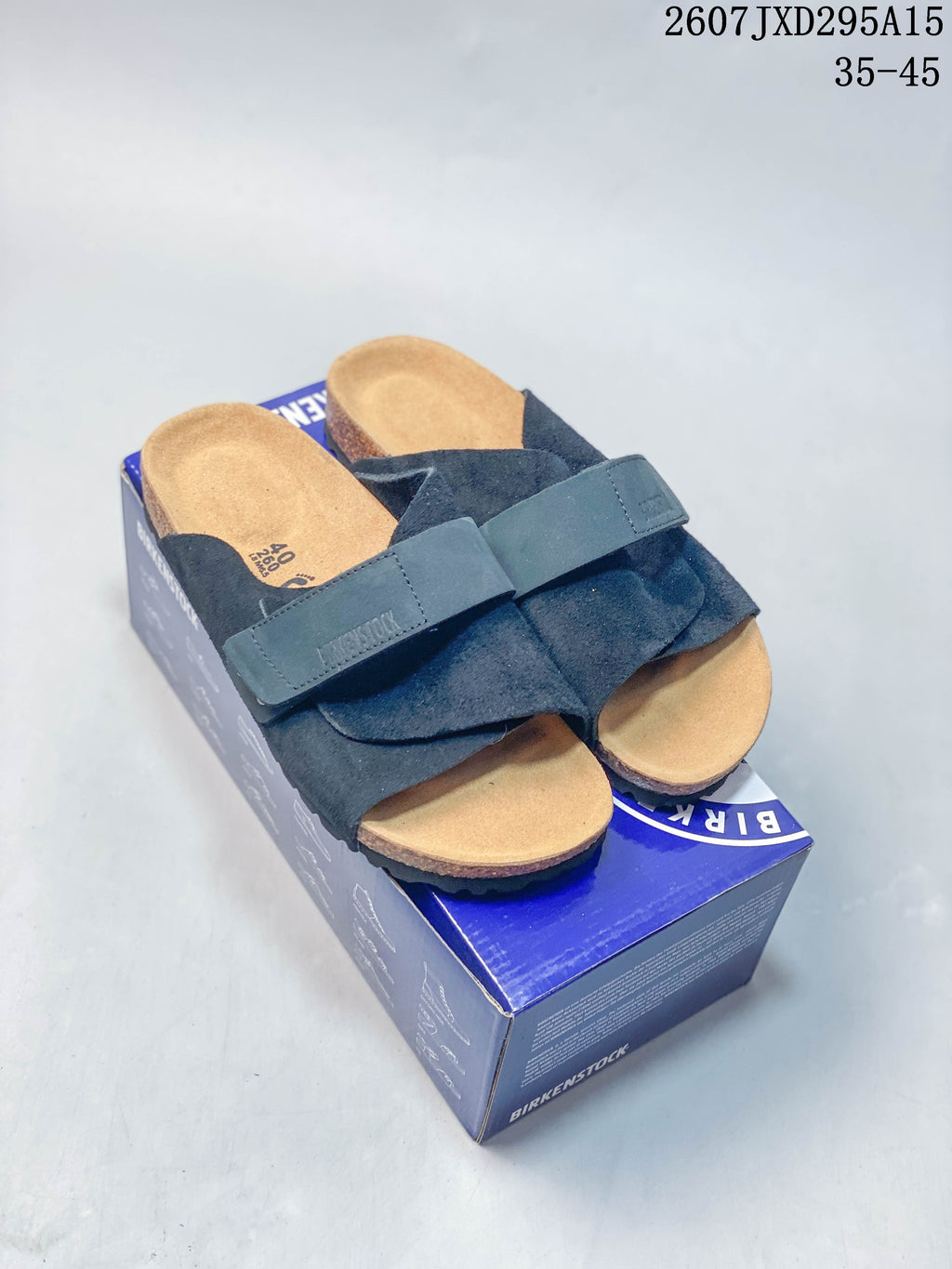 Pair of dark crossover sandals displayed on a Birkenstock-branded box, with the product code and size range visible above.