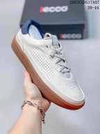 Angled side view of the white ECCO sneaker showing perforated leather panels, white laces, navy heel detail, and a gum-colored rubber sole.