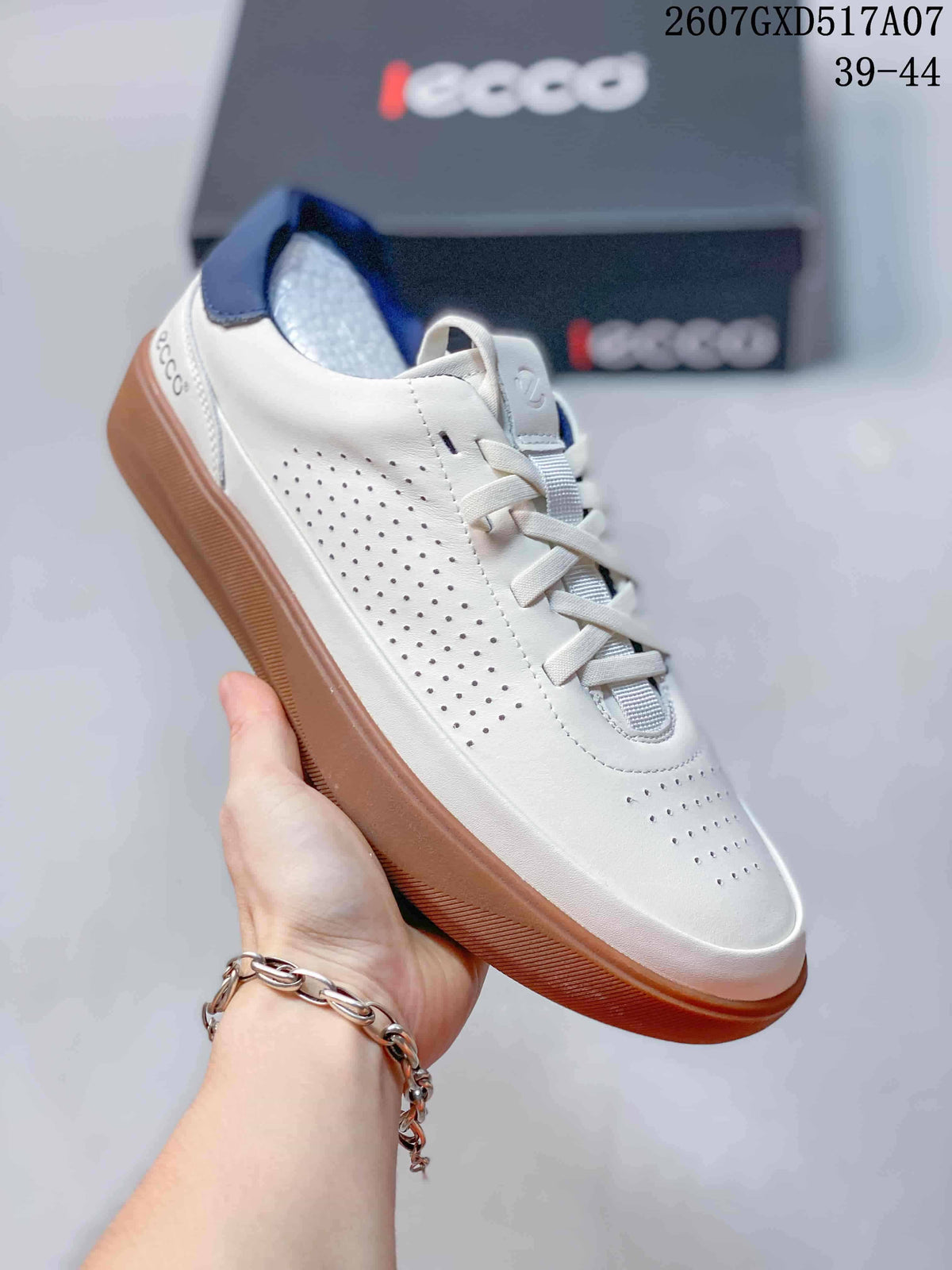Angled side view of the white ECCO sneaker showing perforated leather panels, white laces, navy heel detail, and a gum-colored rubber sole.