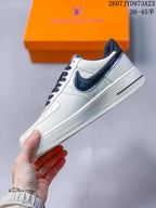 Side profile showing the white low-top sneaker, dark textured Swoosh, white midsole, and navy collar trim.