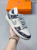 Angled side view showing the sneaker's white and grey upper, navy patterned panels, and low-top silhouette.