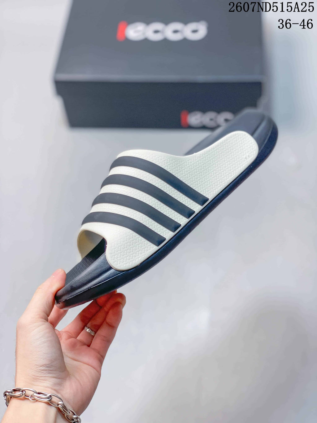 Side view of a navy and white slide sandal showing the layered upper bands and outsole profile.