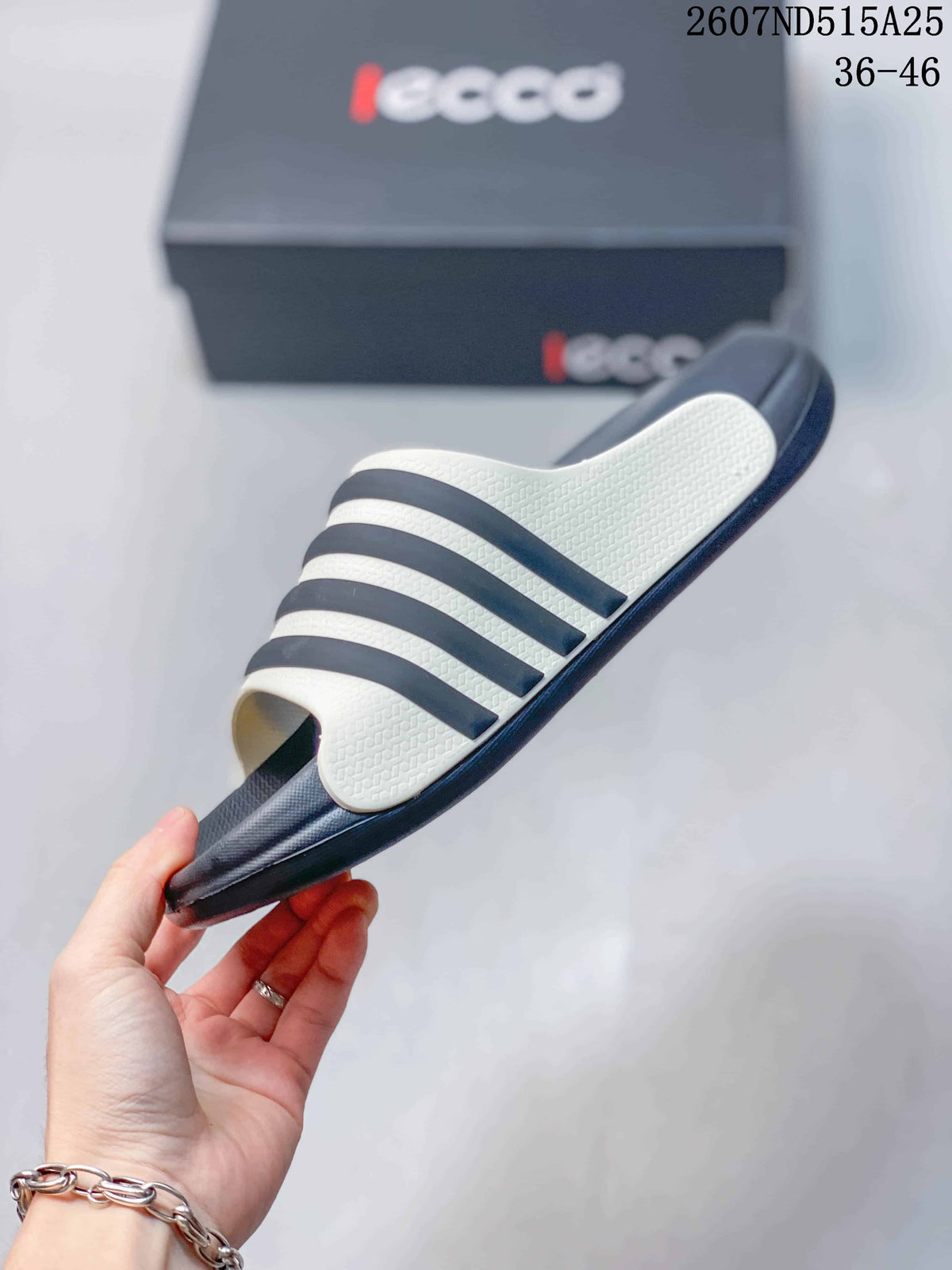 Side view of a navy and white slide sandal showing the layered upper bands and outsole profile.