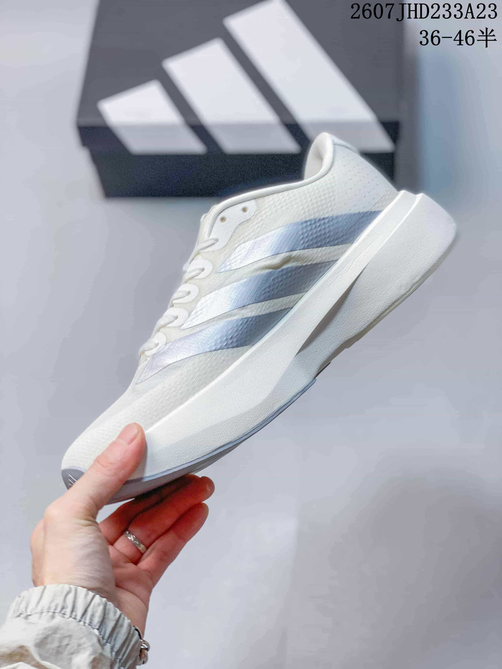 Side profile of the white low-top sneaker showing layered light blue-gray side stripes and a raised midsole.