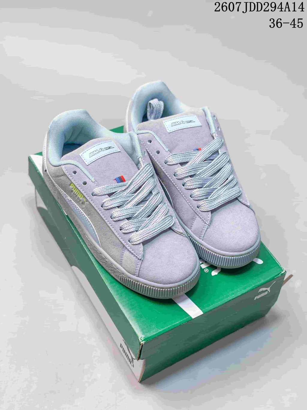 Pair of light gray-lilac PUMA Suede XL sneakers displayed on a green shoebox; the image shows style code 2607JDD294A14 and size range 36-45.