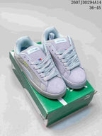 Pair of light gray-lilac PUMA Suede XL sneakers displayed on a green shoebox; the image shows style code 2607JDD294A14 and size range 36-45.