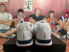 Rear view of white Nike basketball shoes with red heel details and a dark midsole accent.