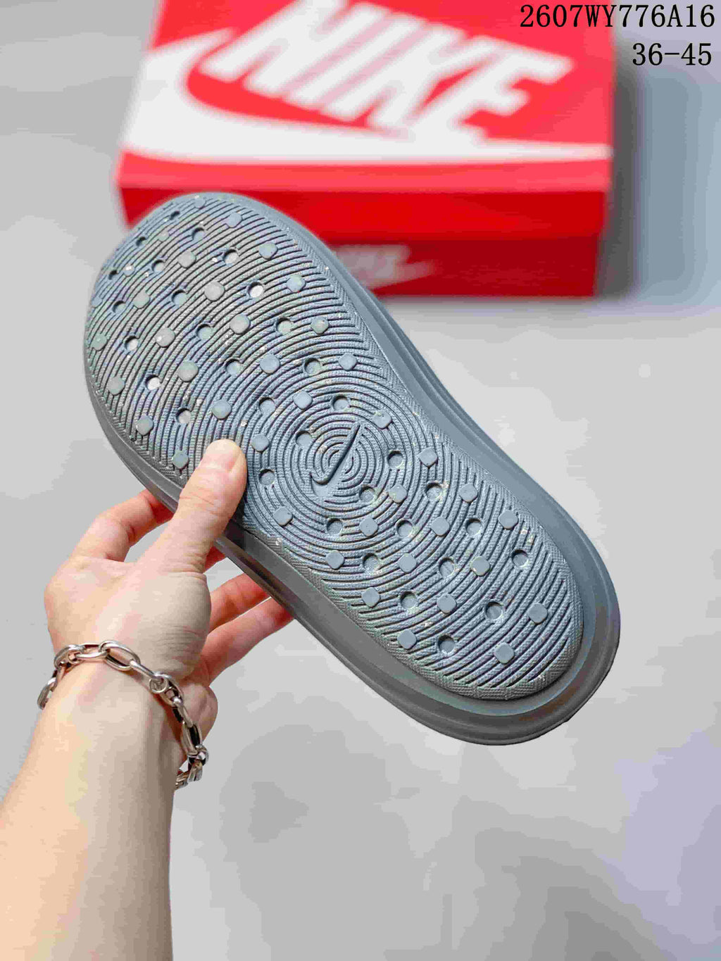 Underside of the gray clog showing a textured outsole with circular traction details.
