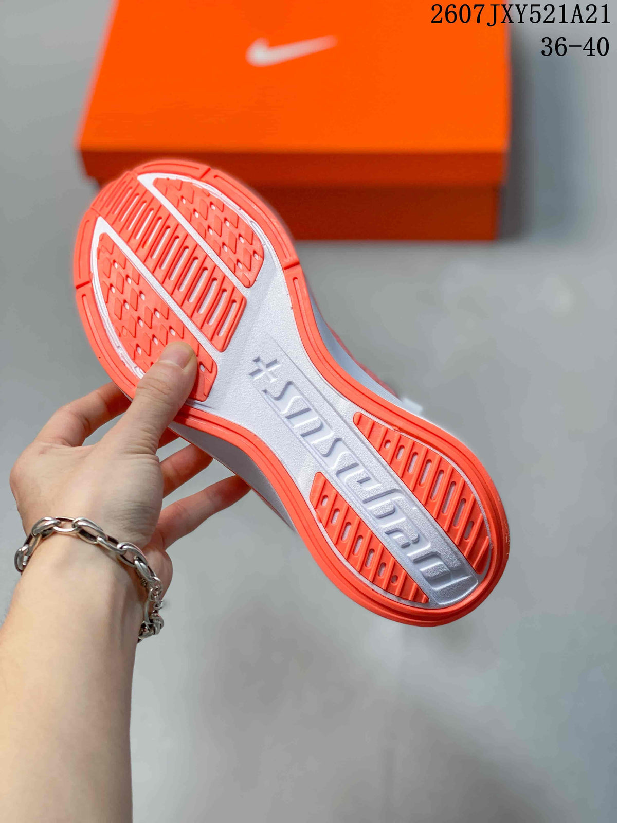 Close-up of the coral and white patterned outsole of a Nike sneaker with an orange shoebox in the background.