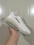 Side view of a white Balenciaga sneaker showing layered panels, black side lettering, a padded tongue, and a translucent sculpted sole.