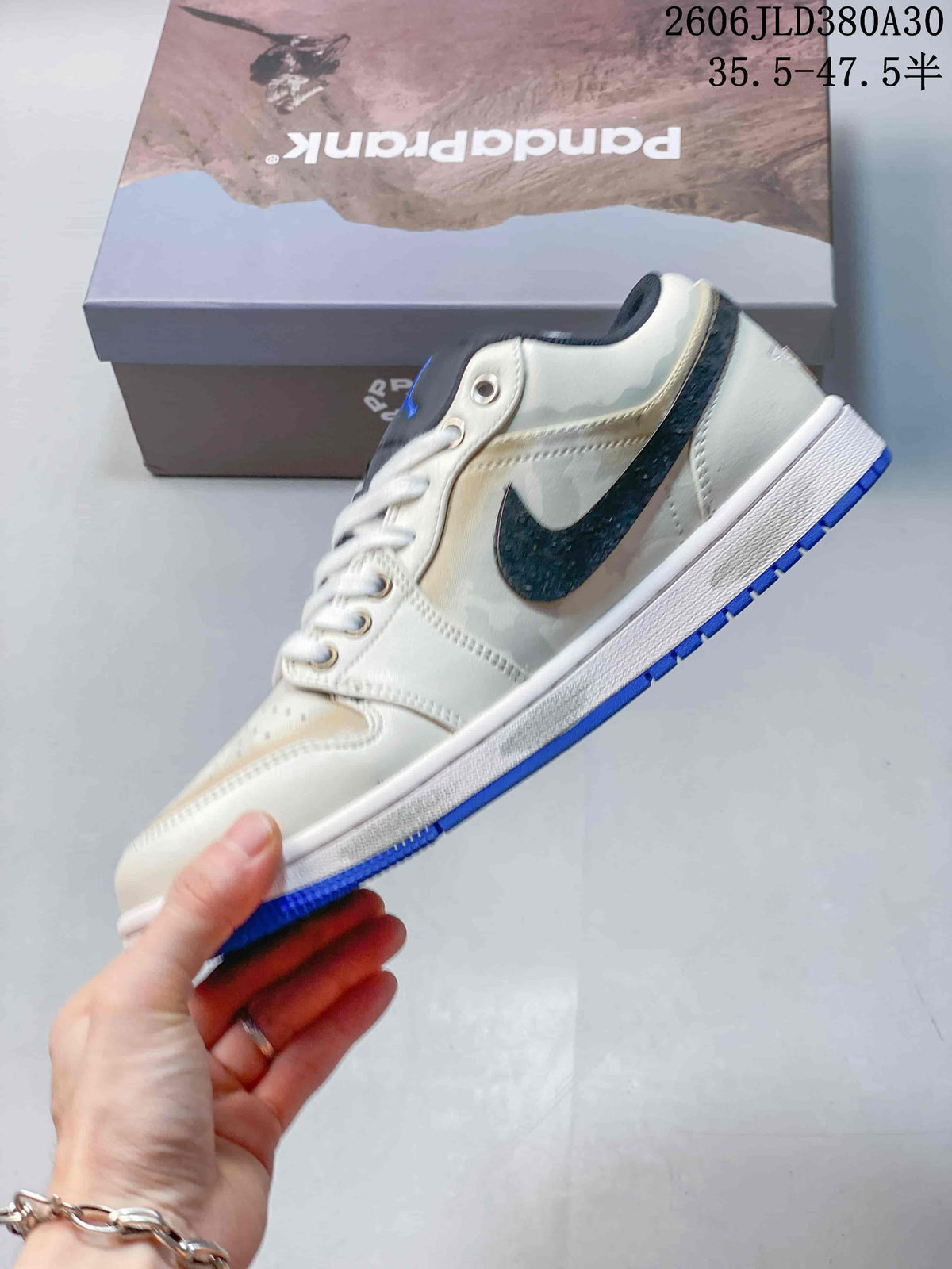 Side profile highlighting the dark textured overlay, off-white panels, and blue outsole.