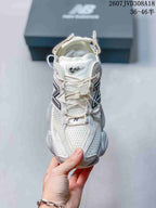 Front view of a white and light gray New Balance 9060 sneaker showing the mesh toe box, laces, tongue branding, and layered upper.