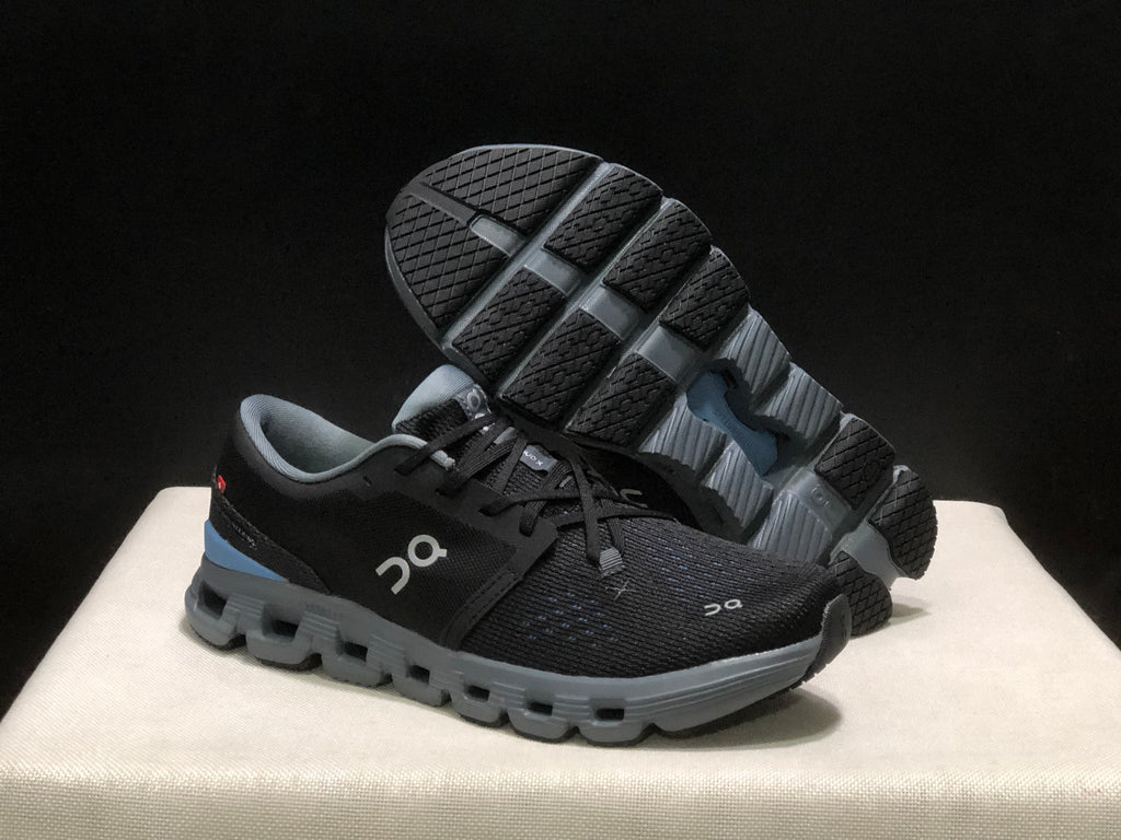 Angled view of the shoes with one outsole lifted to show the tread pattern.