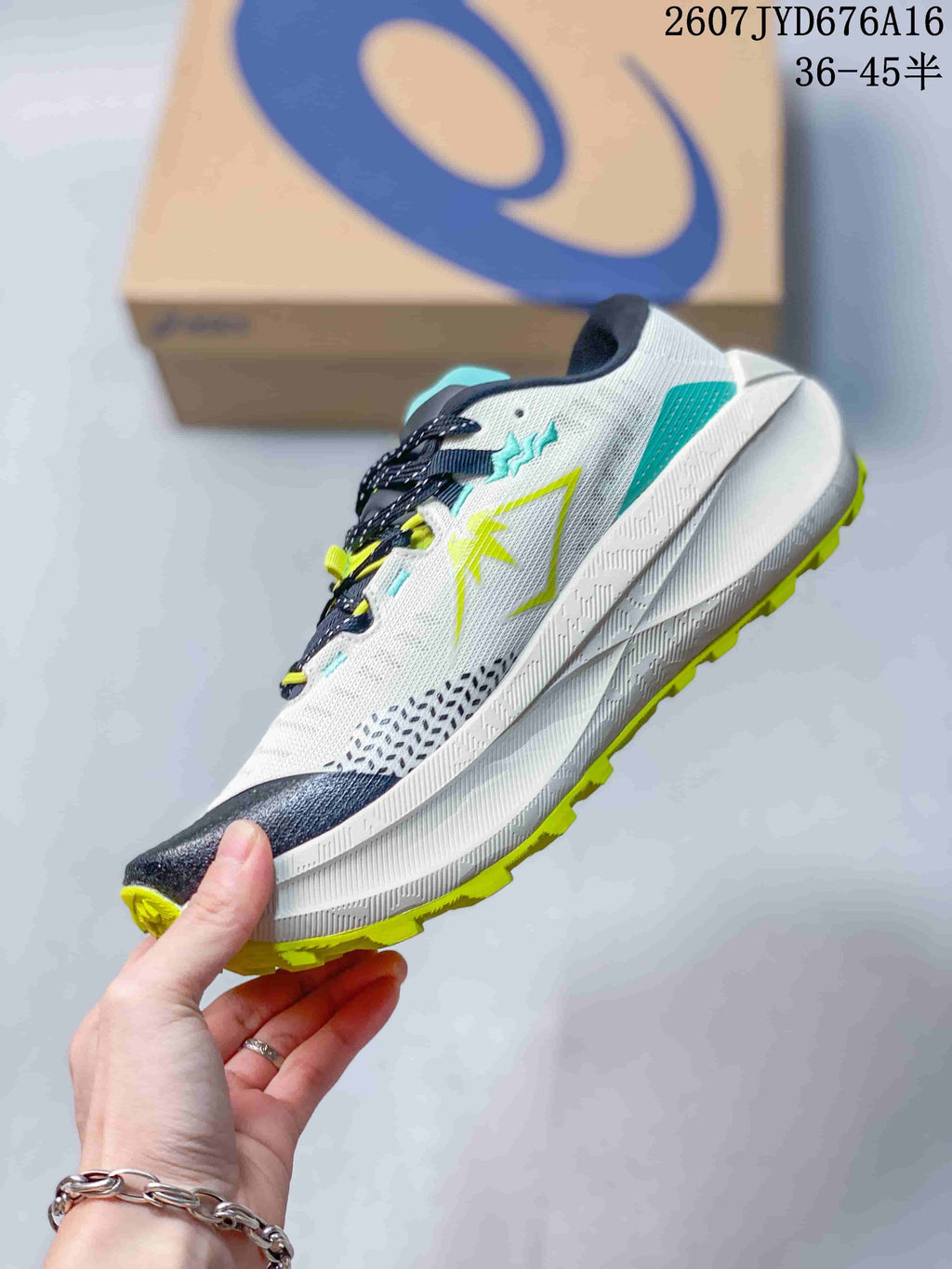 Side view of the white ASICS trail running shoe with lime and turquoise overlays, dark toe detailing, and a layered white midsole.