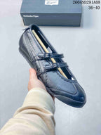 Angled close-up of the black Onitsuka Tiger sneaker showing its buckle straps, stitched side panels, and low-profile sole.