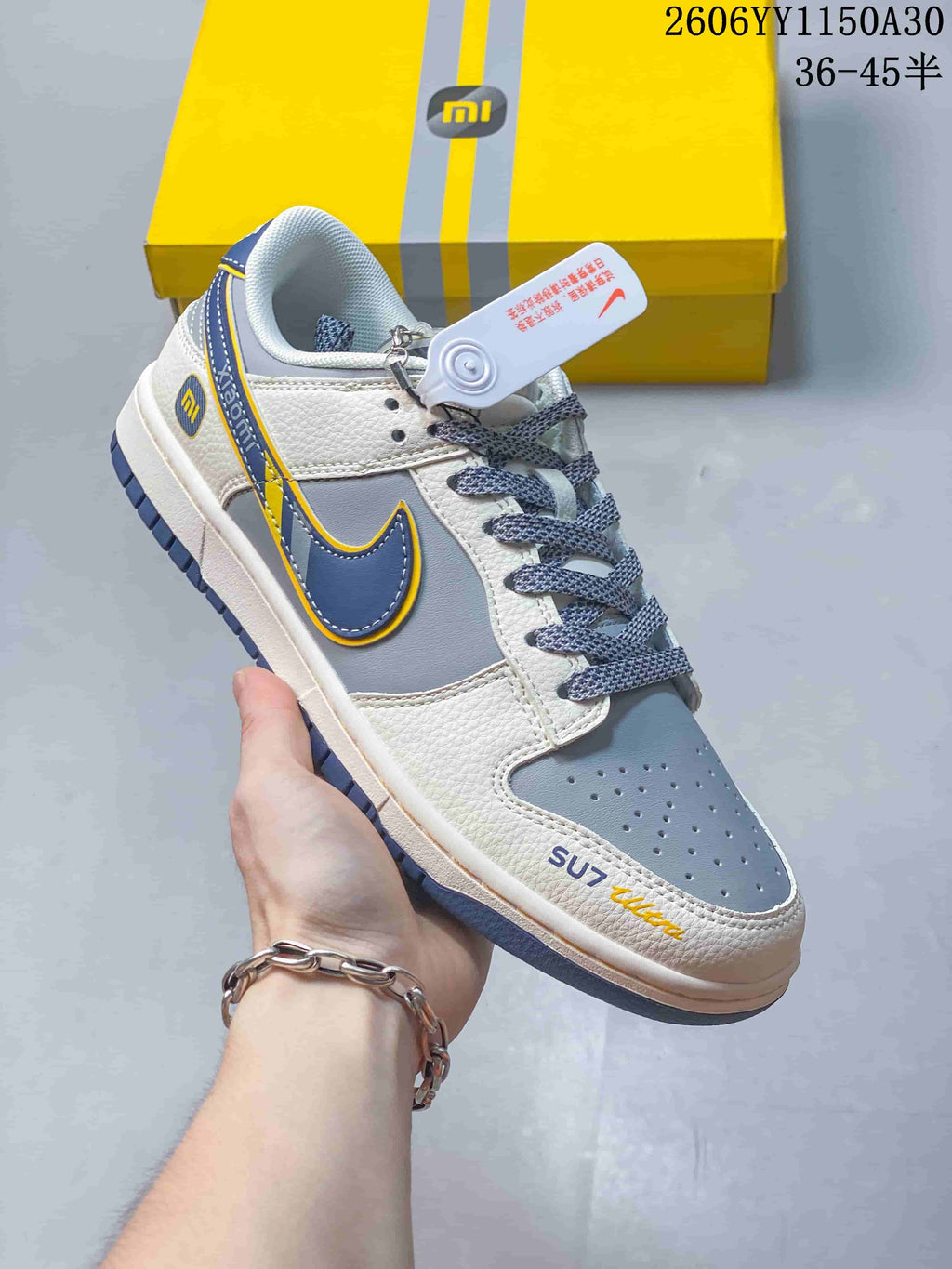 Side view of a white and gray low-top sneaker with navy and yellow accents