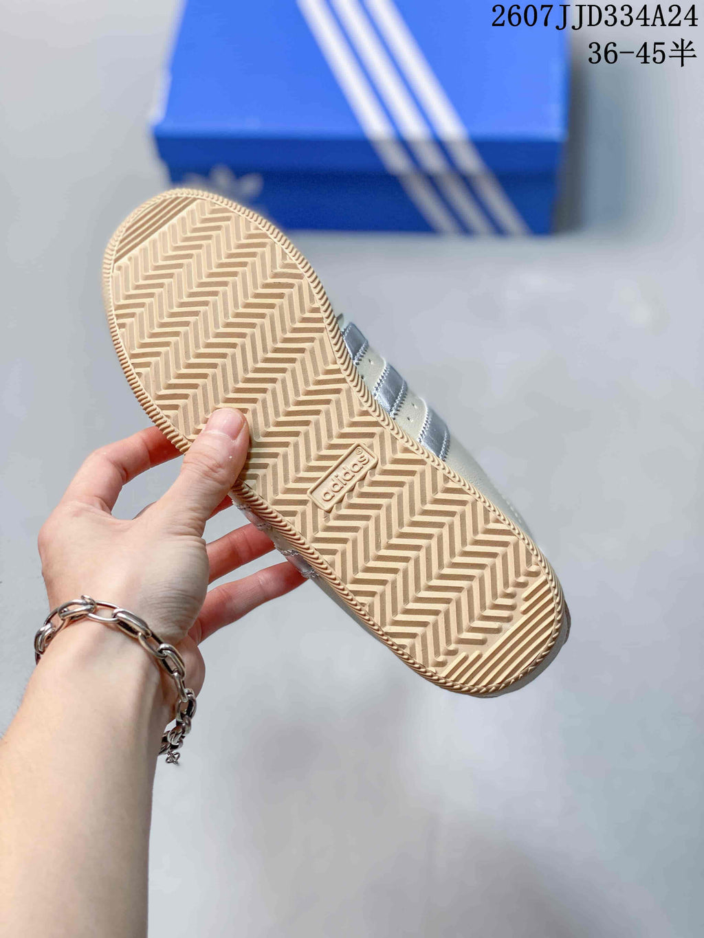 Close view of the sneaker outsole showing a gum-colored herringbone tread pattern and adidas branding.