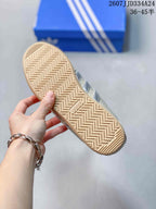 Close view of the sneaker outsole showing a gum-colored herringbone tread pattern and adidas branding.