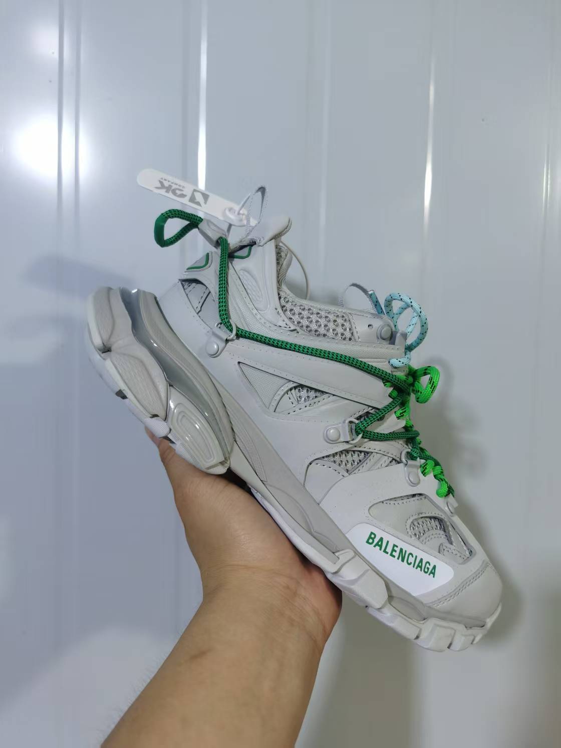 Angled side view of the Balenciaga Track Trail sneaker showing the green branding, blue and green laces, and segmented outsole.