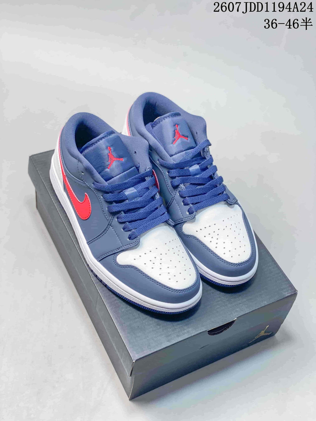 Pair of navy, red, and white Jordan Air Jordan 1 Low sneakers displayed on a shoebox.