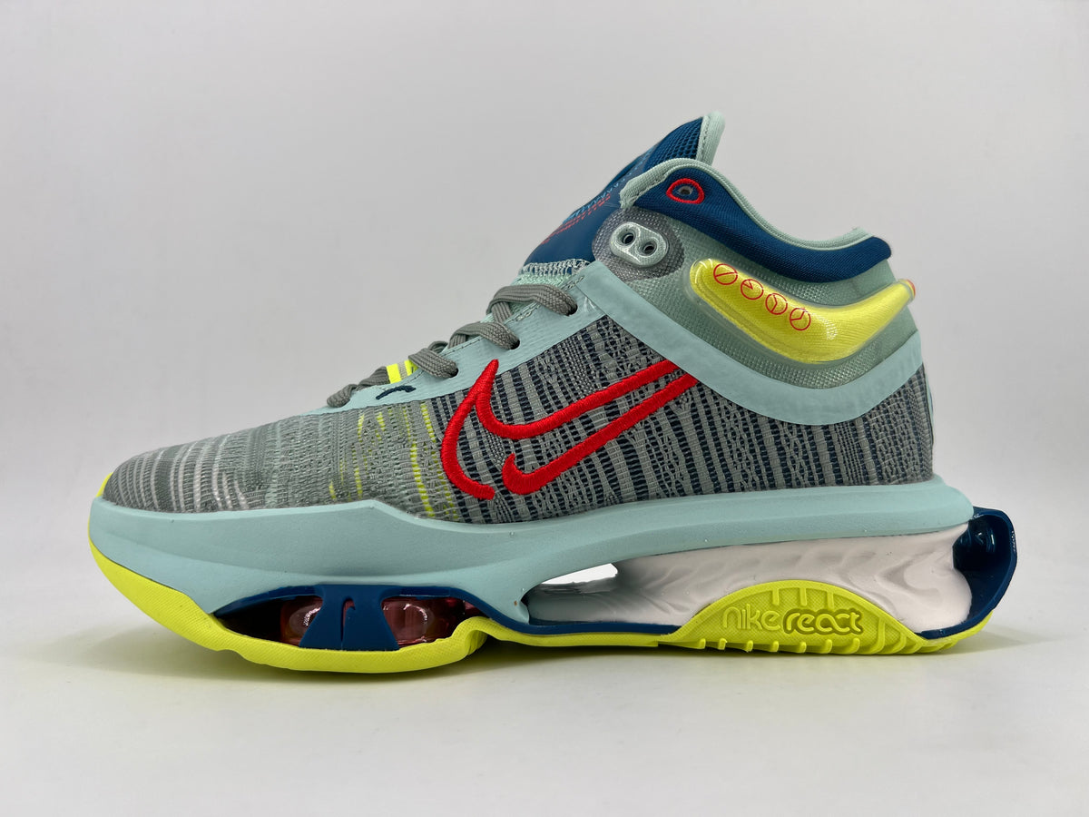 Side view of a gray patterned Nike shoe with red Swoosh detailing, pale blue overlays, navy accents, neon yellow details, and a sculpted sole.