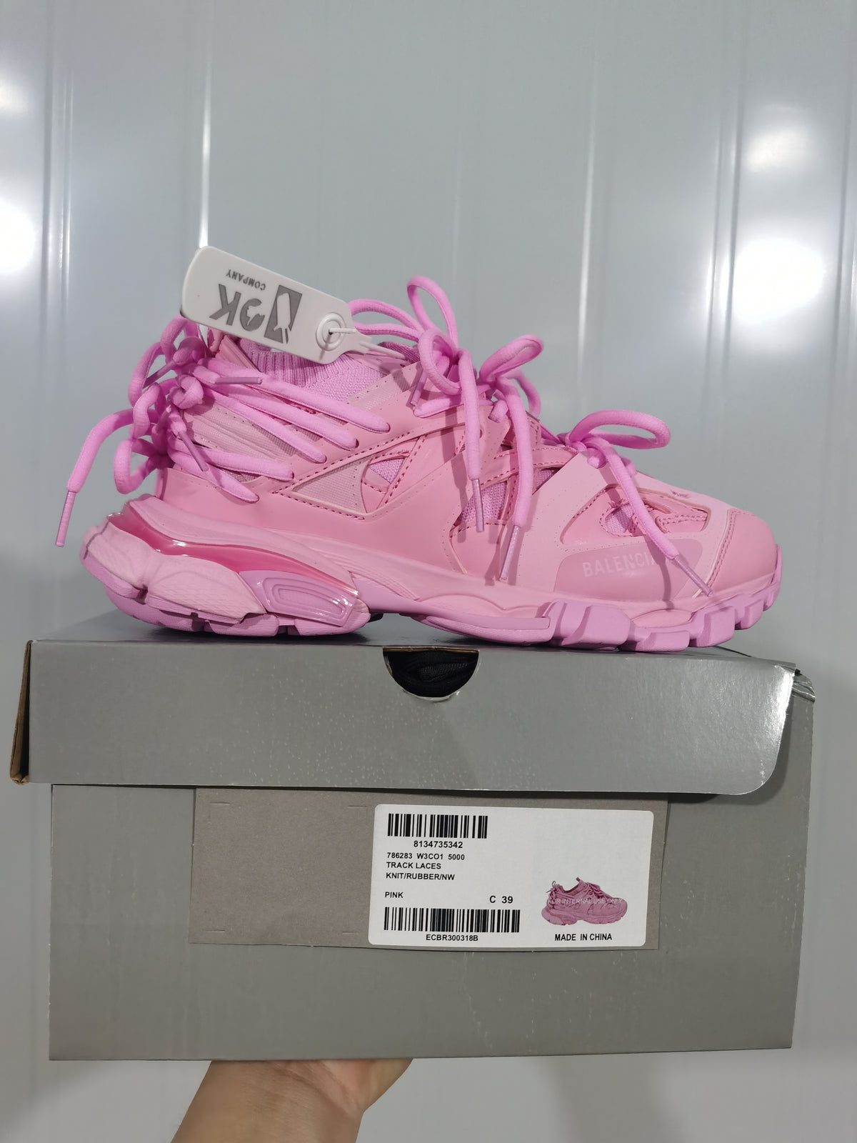 Side view of the pink sneaker displayed on its box; the label shows TRACK LACES, PINK and size C 39.