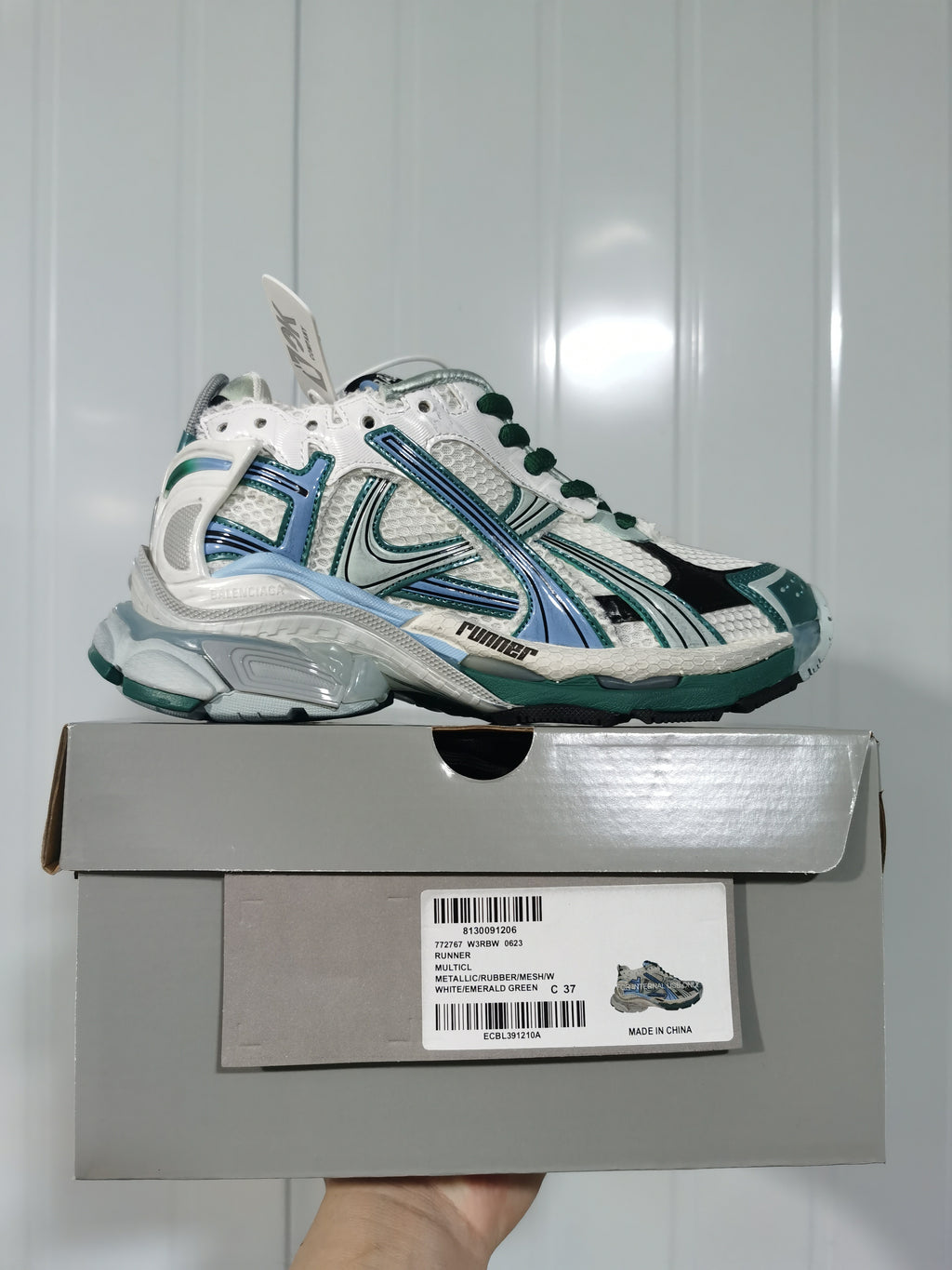 Side view of the Balenciaga Runner sneaker above its box, with the box label showing Runner, White/Emerald Green, code 0623, and size 37.