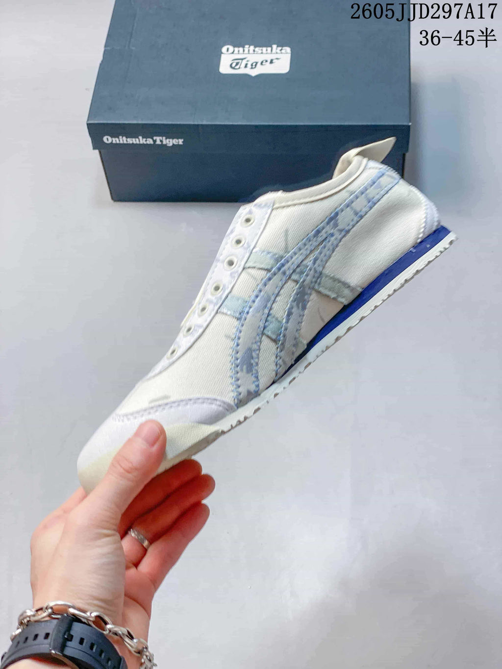 Side profile of the off-white sneaker showing pale blue side stripes, stitched panels and a blue heel accent; JJD297A17 and the size range 36–45.5 are visible.