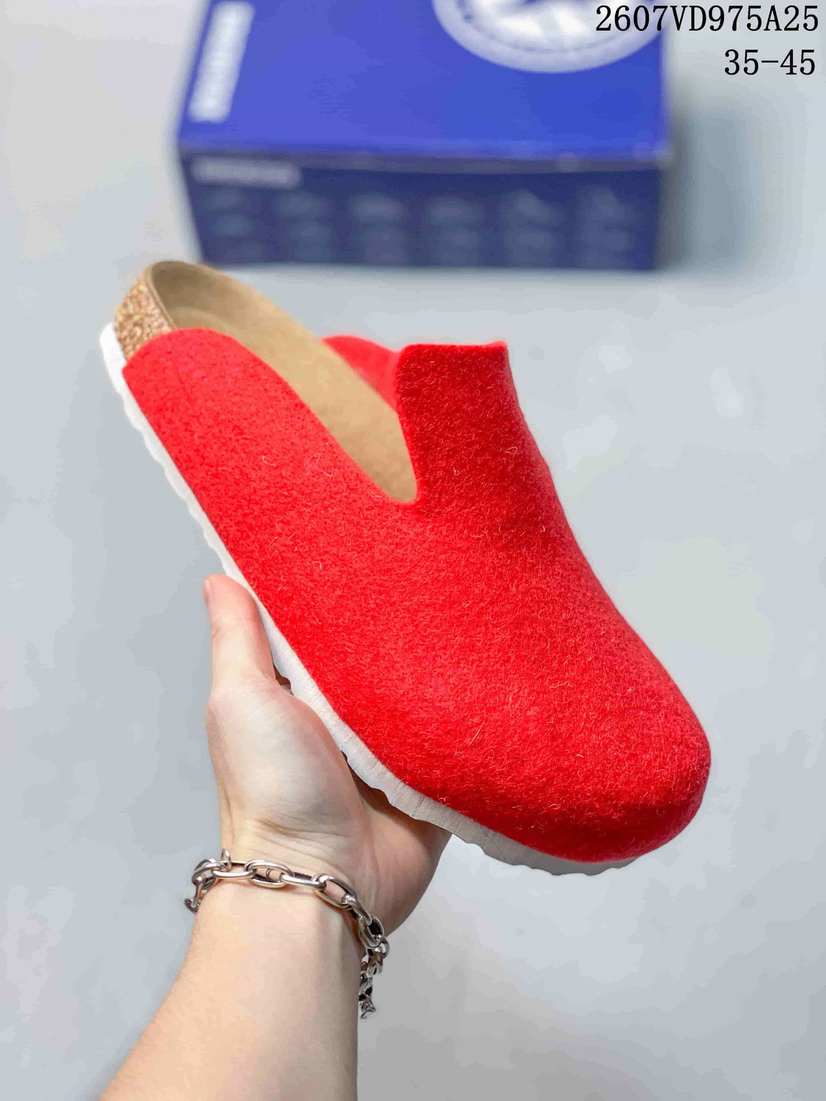 Close-up of a red closed-toe slip-on clog showing its textured upper and contrasting sole.