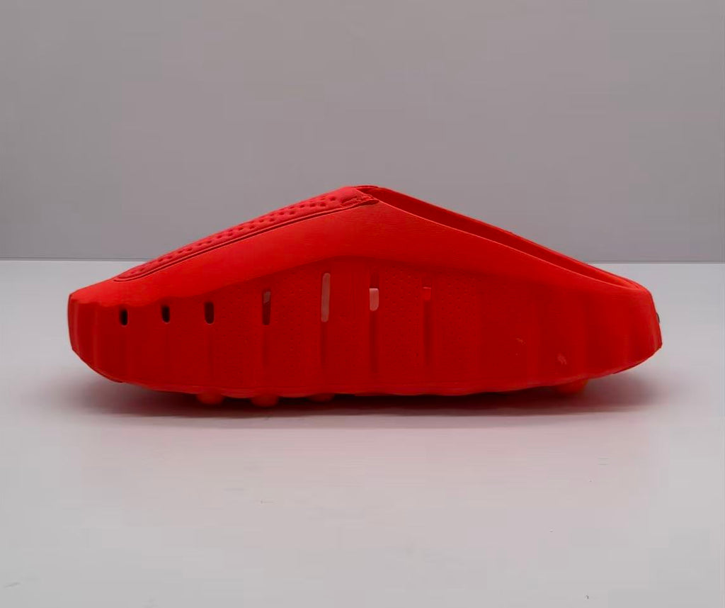 Side view highlighting perforations and openings along the orange-red Nike slide.