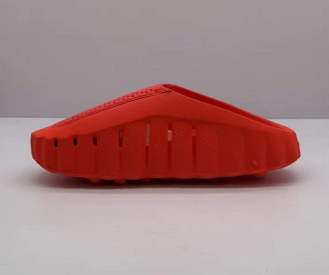 Side view highlighting perforations and openings along the orange-red Nike slide.