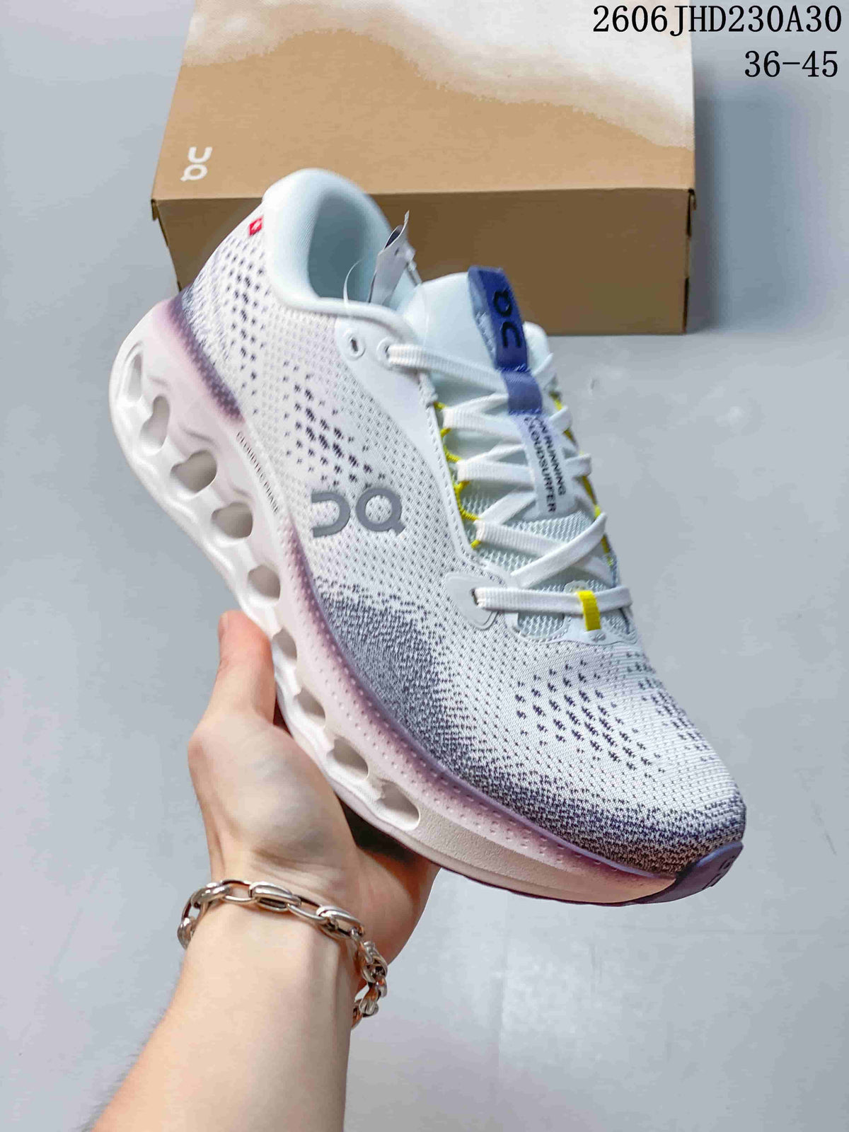 Close-up of a white On Cloudtilt shoe with purple and yellow accents and a sculpted sole.