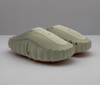 Pair of beige Nike slip-on sandals shown from a front three-quarter angle.