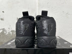 Rear view of black high-top basketball shoes with tonal heel graphics and sculpted soles.