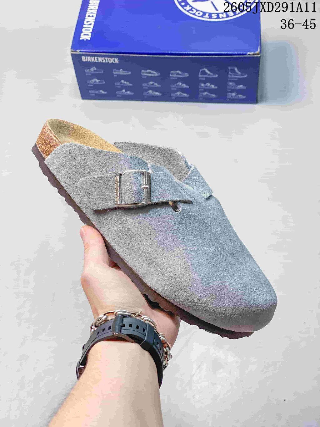 Gray-blue suede-like closed-toe sandal with an adjustable buckle, shown beside a Birkenstock-branded box.
