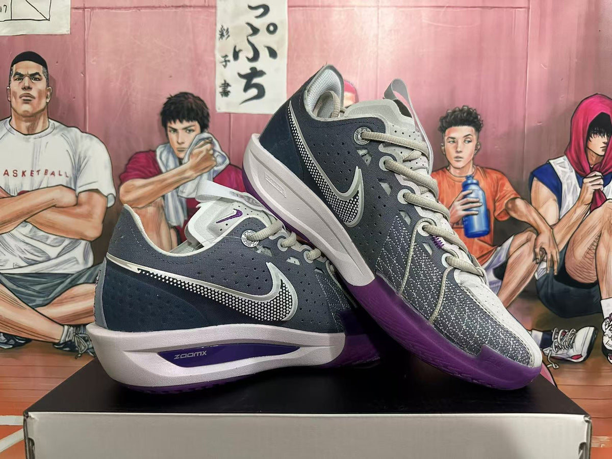 Pair of Nike basketball shoes displayed at an angle, showing gray laces, dark panels, and purple outsoles.
