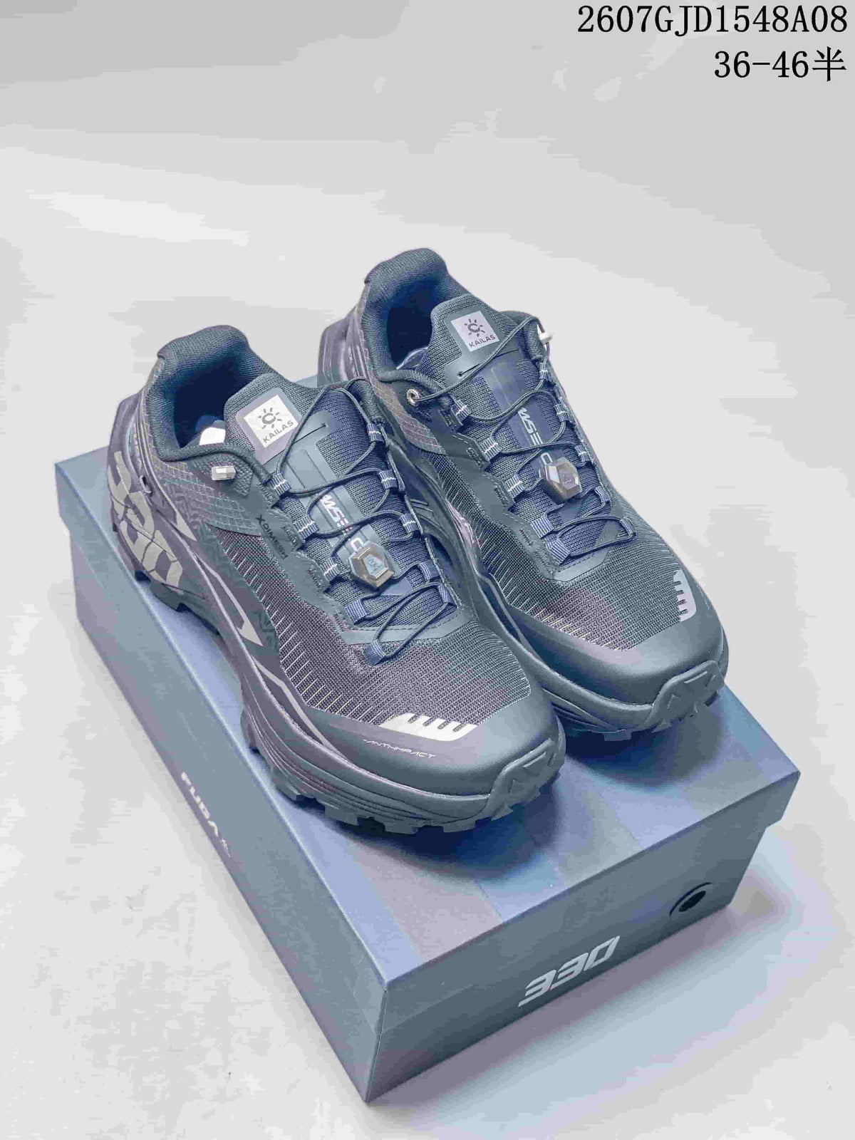 Pair of dark gray Kailas Fuga Ex 330 trail shoes displayed on a shoe box, with product code and size range overlaid.