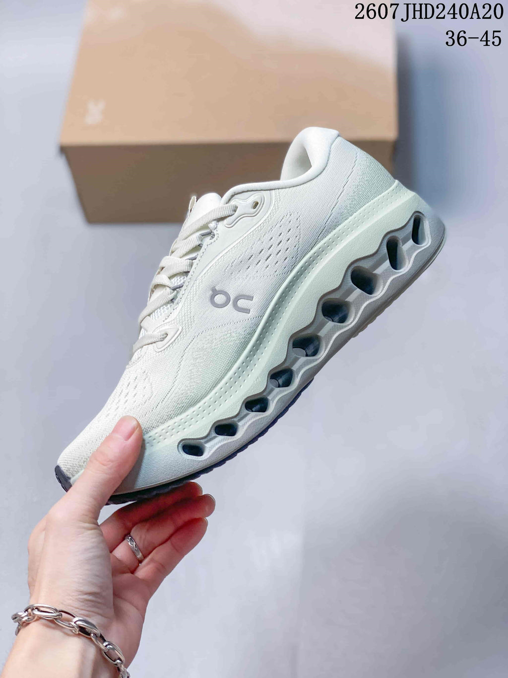 Side view of a white On sneaker showing the textile upper, side branding and sculpted open-channel outsole.