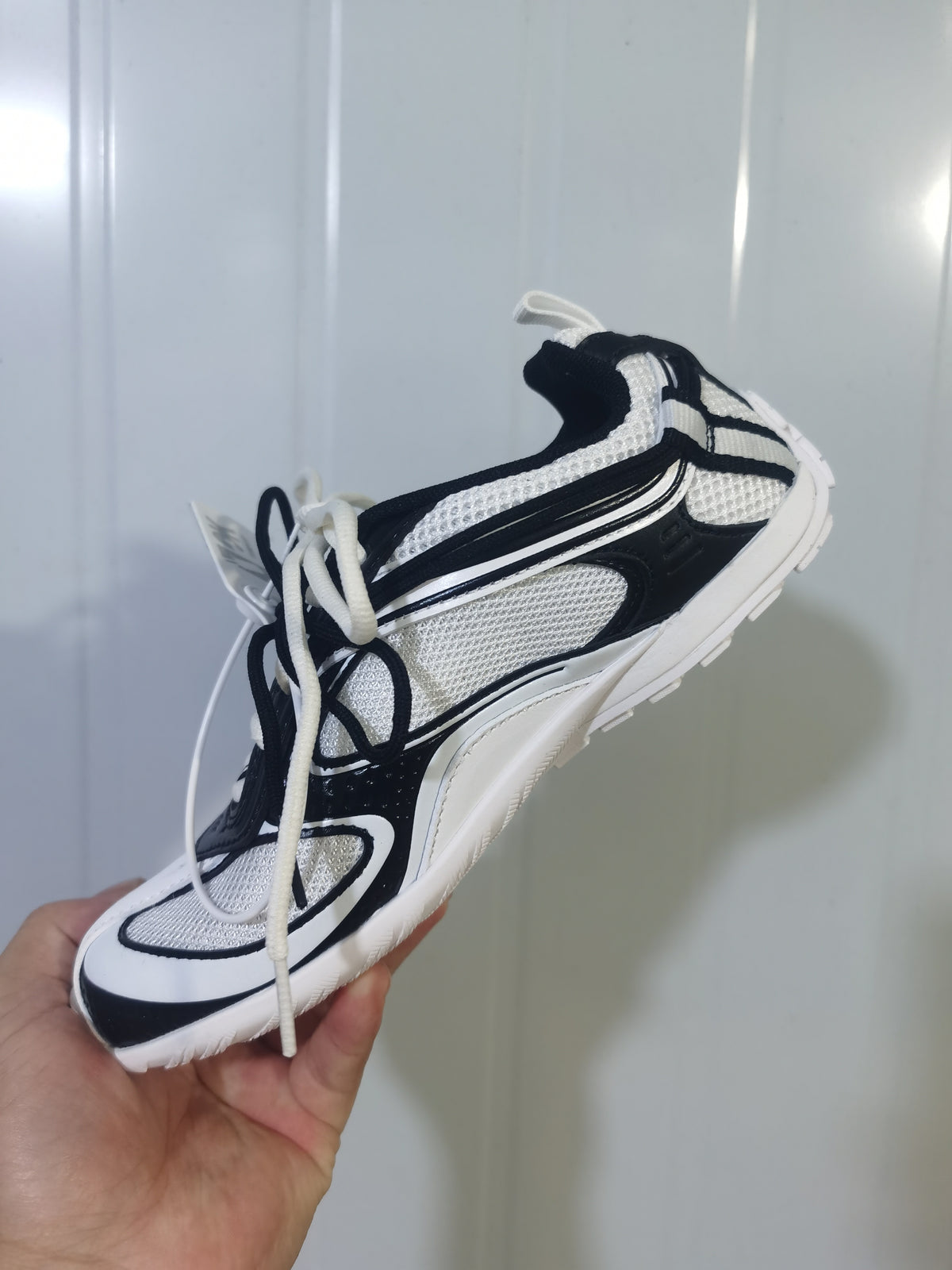 White and black Balenciaga Radar sneaker shown from an angled side view with layered panels, mesh sections and contrasting laces.