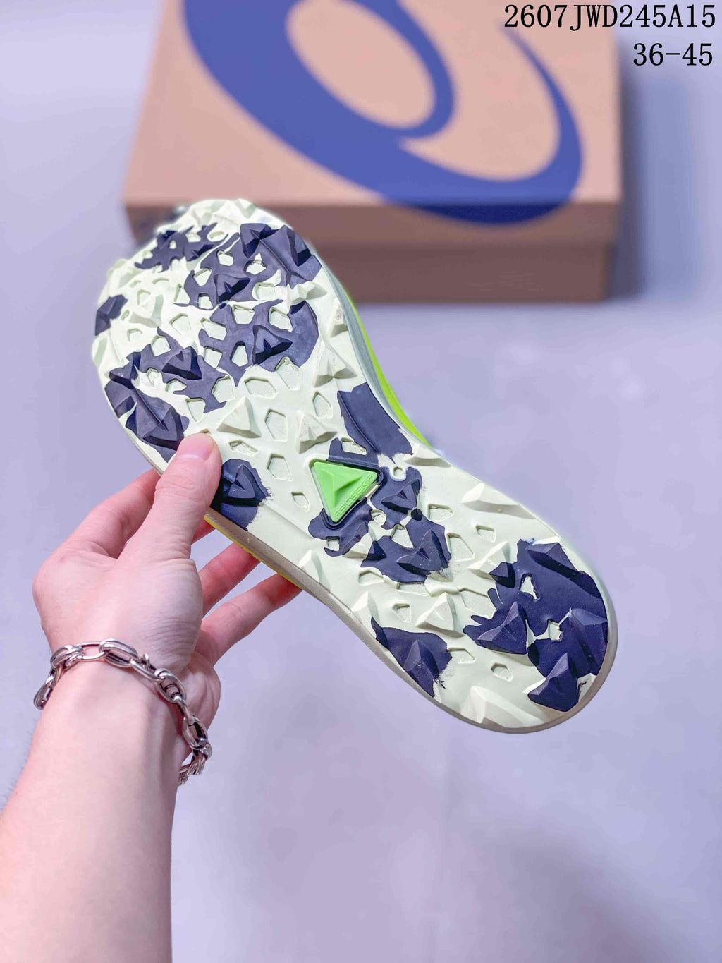 Bottom view of the sneaker showing a patterned white and dark outsole with neon green details.