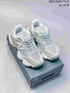 Pair of New Balance 9060 sneakers in pale mint green, white and gray, displayed on a shoebox.