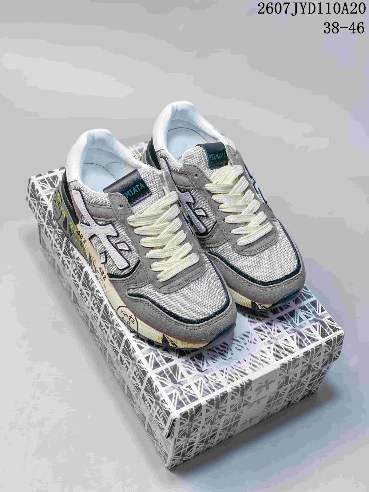 Pair of grey and white Premiata sneakers displayed on a patterned shoebox, with model code and size range visible above.