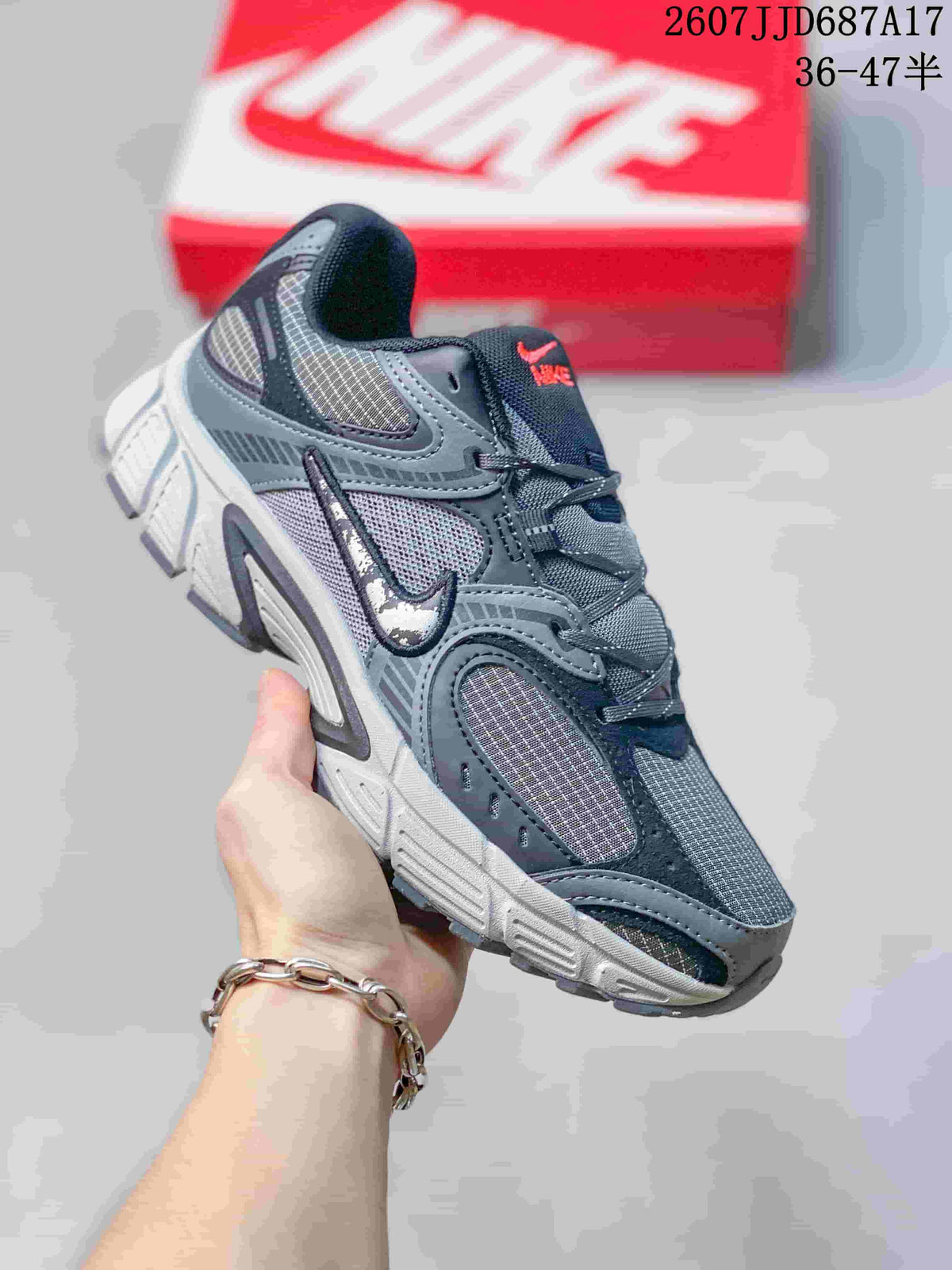 Three-quarter side view of a gray Nike V5 RNR sneaker showing the layered upper, side logo, and segmented outsole.